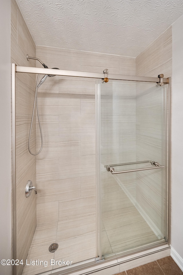 bathroom with tile patterned floors, a textured ceiling, and walk in shower