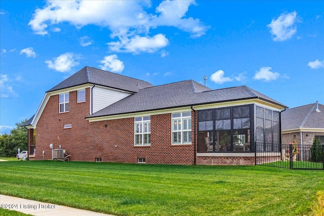 rear view of property featuring a sunroom and a yard