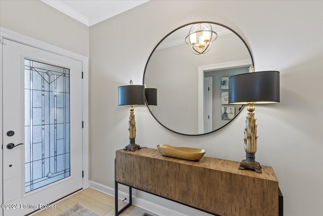 tiled entryway with a notable chandelier and crown molding