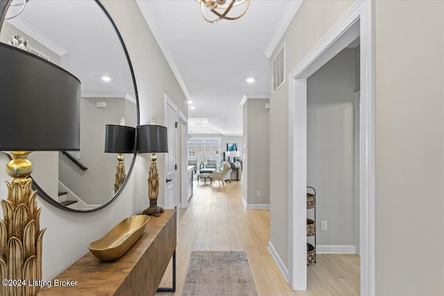 corridor with light wood-type flooring and crown molding