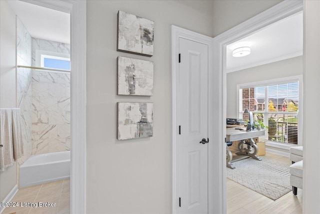 hall with light wood-type flooring, crown molding, and a wealth of natural light