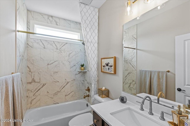 full bathroom featuring tiled shower / bath combo, vanity, and toilet