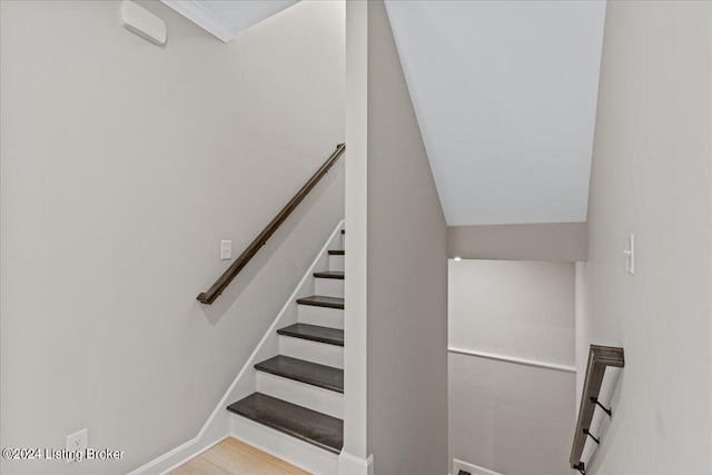 staircase with wood-type flooring and lofted ceiling