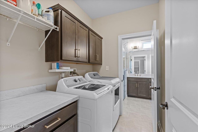 clothes washing area featuring sink, washing machine and clothes dryer, and cabinets