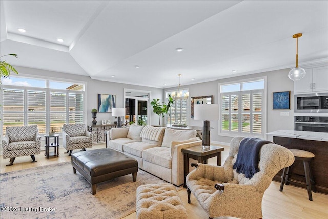 living room with light wood-type flooring, ornamental molding, and a notable chandelier