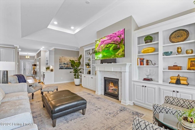 living room featuring light wood-type flooring, a tray ceiling, and built in features