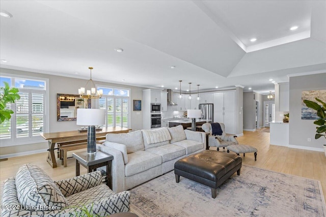 living room with light hardwood / wood-style flooring, vaulted ceiling, an inviting chandelier, and crown molding