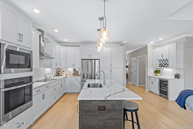 kitchen featuring white cabinetry, an island with sink, wine cooler, stainless steel appliances, and wall chimney range hood