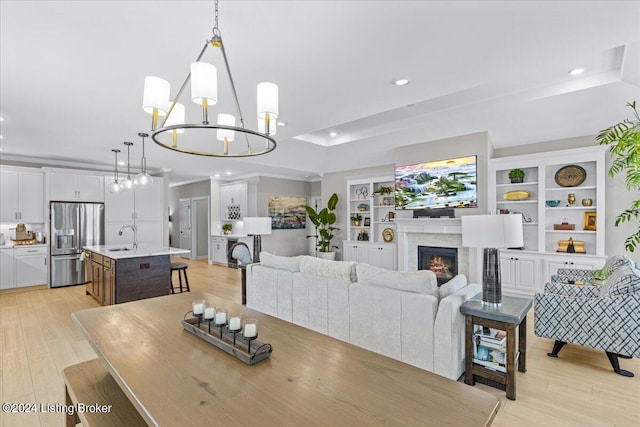 dining room with light hardwood / wood-style floors, sink, a chandelier, and a premium fireplace