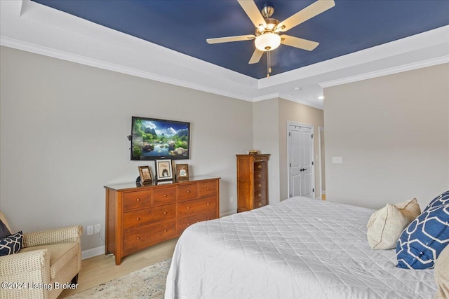 bedroom featuring a raised ceiling, ornamental molding, ceiling fan, and light hardwood / wood-style flooring