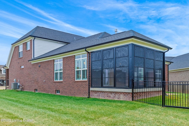 view of home's exterior with a sunroom, central AC, and a lawn