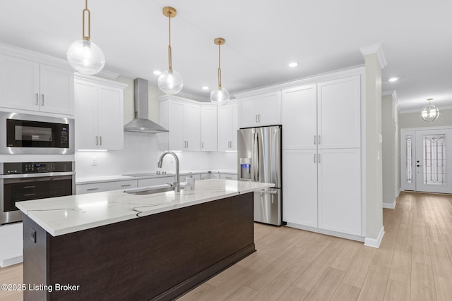 kitchen featuring black appliances, decorative light fixtures, white cabinets, and wall chimney exhaust hood