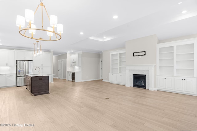 unfurnished living room with wine cooler, sink, a raised ceiling, and light hardwood / wood-style floors