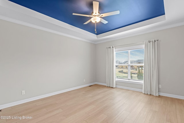 spare room featuring ceiling fan, a tray ceiling, and light hardwood / wood-style flooring