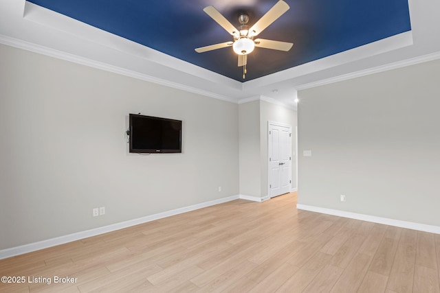 unfurnished room with crown molding, light hardwood / wood-style flooring, ceiling fan, and a tray ceiling