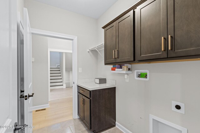 laundry room with cabinets, electric dryer hookup, hookup for a washing machine, and light hardwood / wood-style flooring