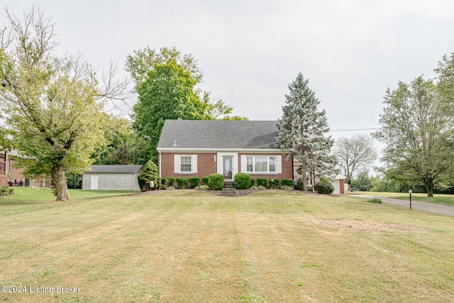 cape cod-style house featuring a front yard and an outbuilding