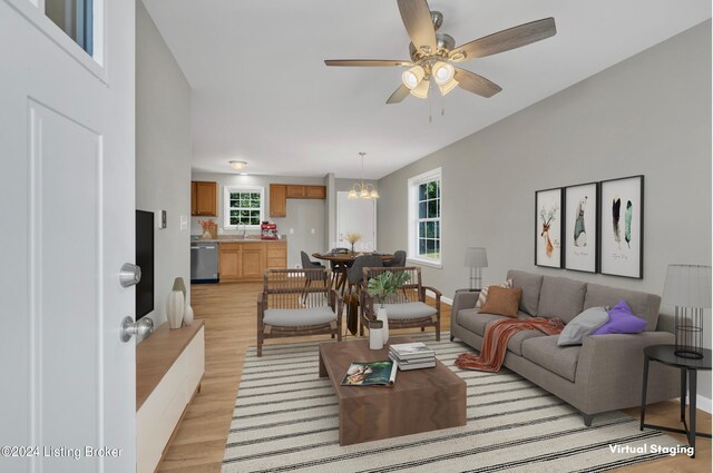 living room with ceiling fan with notable chandelier, light hardwood / wood-style floors, and a healthy amount of sunlight