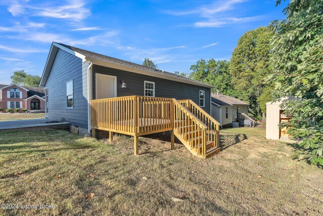 back of property featuring a deck and a lawn