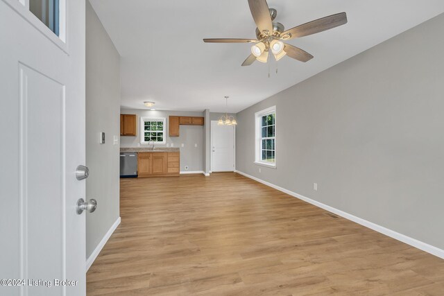 unfurnished living room with ceiling fan with notable chandelier, sink, and light hardwood / wood-style floors