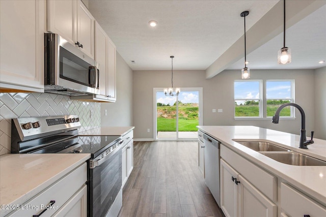 kitchen with stainless steel appliances, a sink, tasteful backsplash, wood finished floors, and light countertops