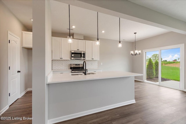 kitchen featuring stainless steel appliances, a sink, dark wood-style flooring, white cabinets, and backsplash