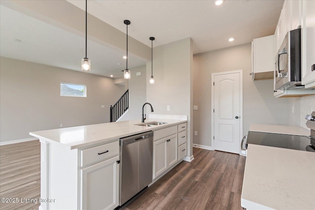 kitchen featuring a sink, stainless steel appliances, dark wood finished floors, white cabinets, and hanging light fixtures