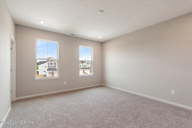 carpeted empty room featuring baseboards
