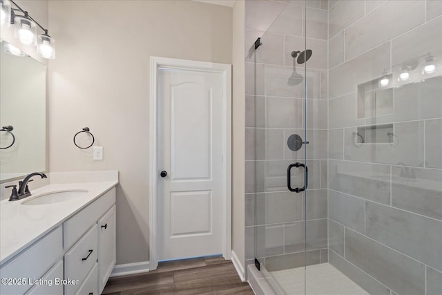 full bathroom featuring a shower stall, vanity, baseboards, and wood finished floors