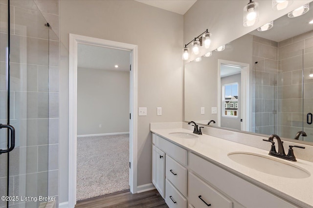 bathroom with a shower stall, wood finished floors, double vanity, and baseboards