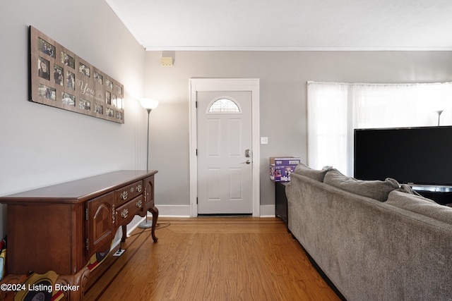 entryway with light wood-type flooring and crown molding