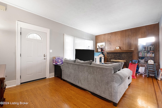 living room with a fireplace, wooden walls, and light hardwood / wood-style floors