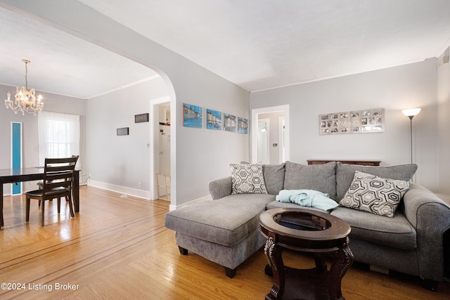 living room featuring wood-type flooring, a chandelier, and crown molding