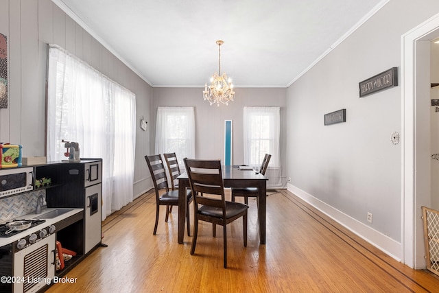 dining room with light wood-type flooring, ornamental molding, an inviting chandelier, and sink