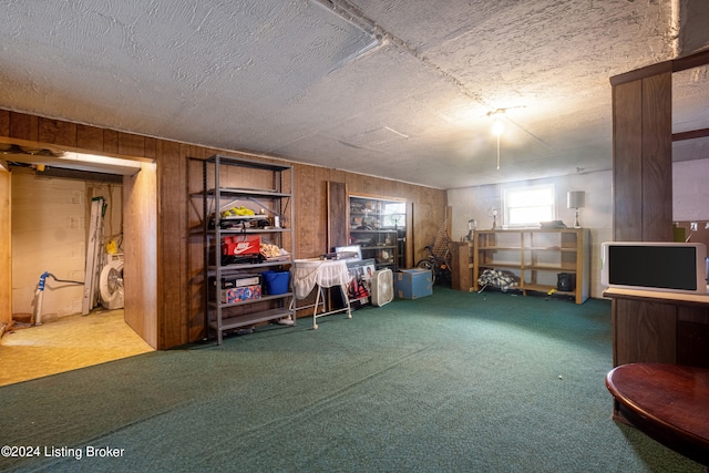 basement with a textured ceiling, washer / clothes dryer, wooden walls, and carpet