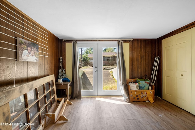 doorway with hardwood / wood-style flooring, wood walls, and french doors