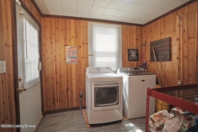 clothes washing area with ornamental molding, wood walls, and independent washer and dryer