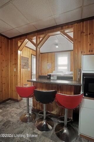 bar featuring a paneled ceiling and wooden walls