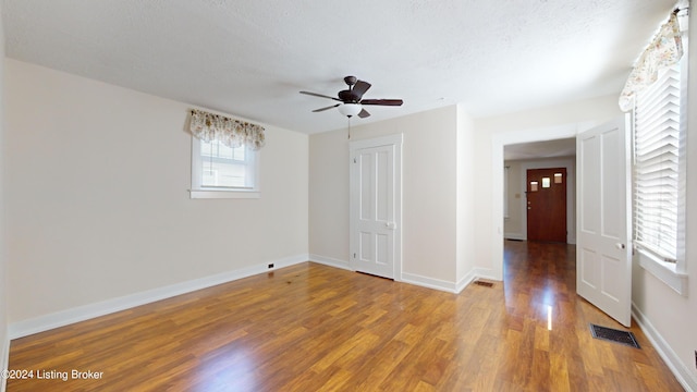 empty room with hardwood / wood-style flooring, ceiling fan, and a textured ceiling