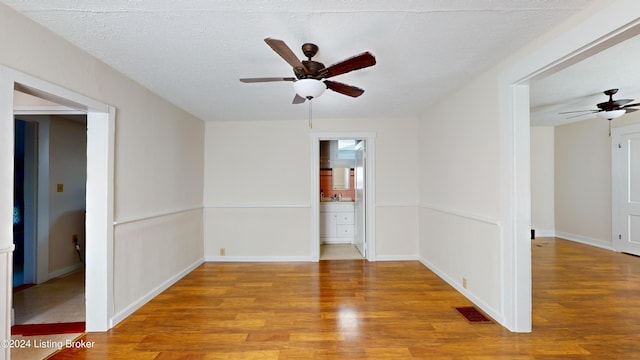 empty room featuring ceiling fan, light hardwood / wood-style floors, and a textured ceiling