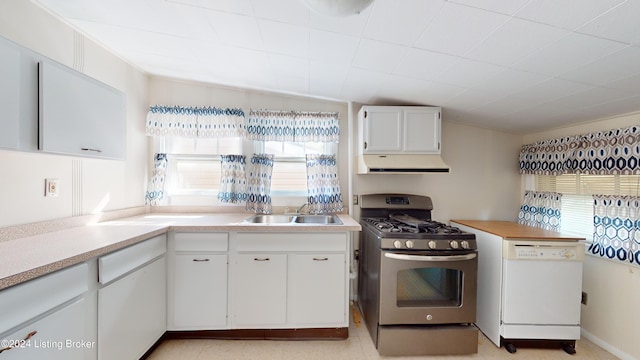 kitchen featuring stainless steel gas range, white dishwasher, sink, white cabinets, and lofted ceiling