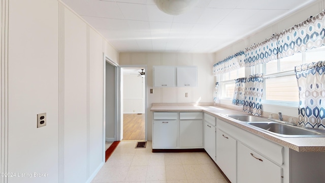 kitchen with white cabinets, ceiling fan, and sink