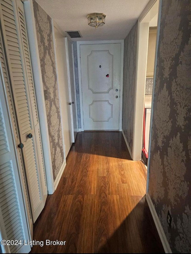 corridor with a textured ceiling and dark hardwood / wood-style flooring