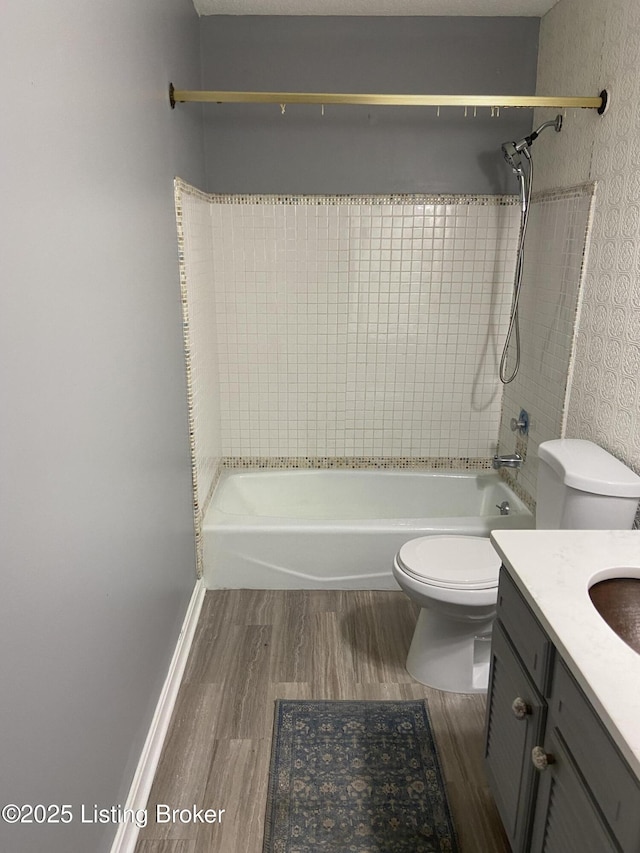 full bathroom with tiled shower / bath, vanity, toilet, and hardwood / wood-style floors