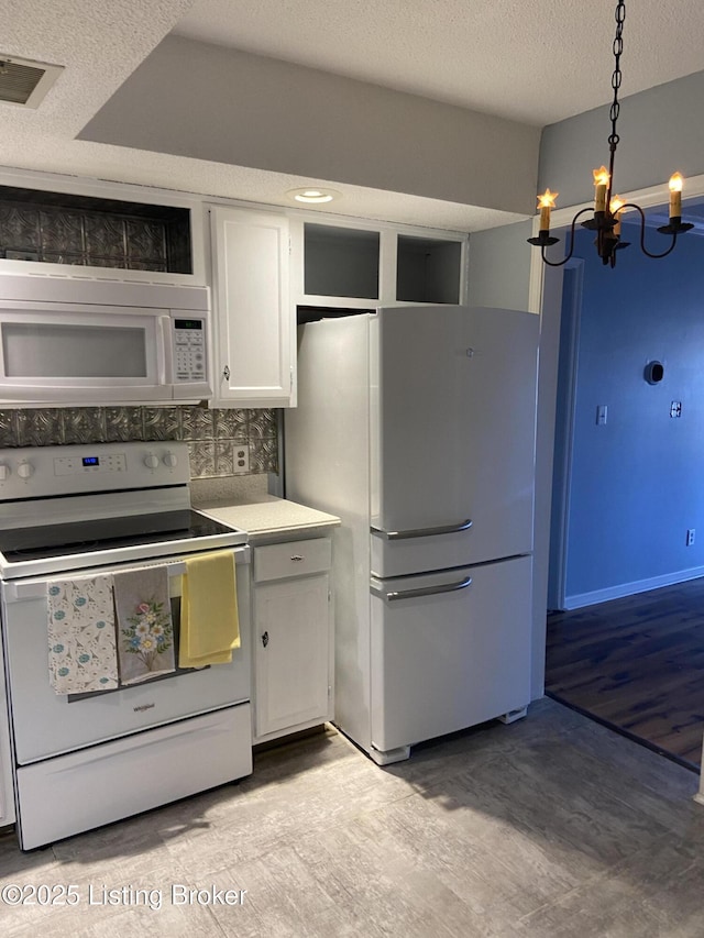 kitchen with white cabinets, hanging light fixtures, white appliances, a notable chandelier, and a textured ceiling