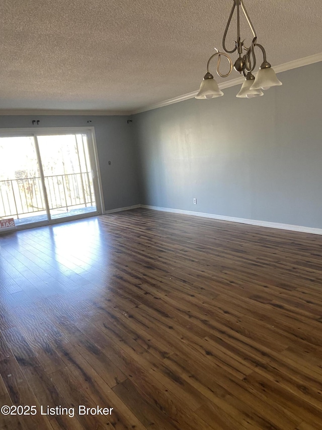 spare room featuring an inviting chandelier, dark wood-type flooring, ornamental molding, and a textured ceiling