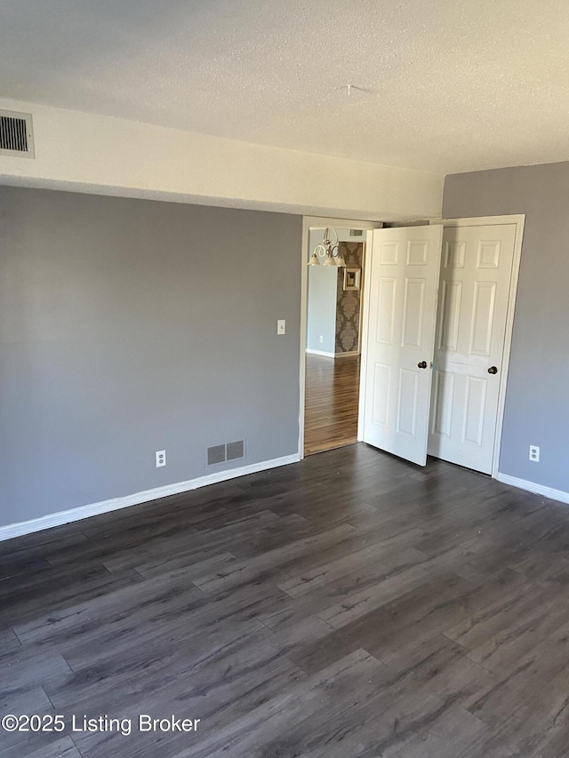 unfurnished room with dark hardwood / wood-style flooring and a textured ceiling