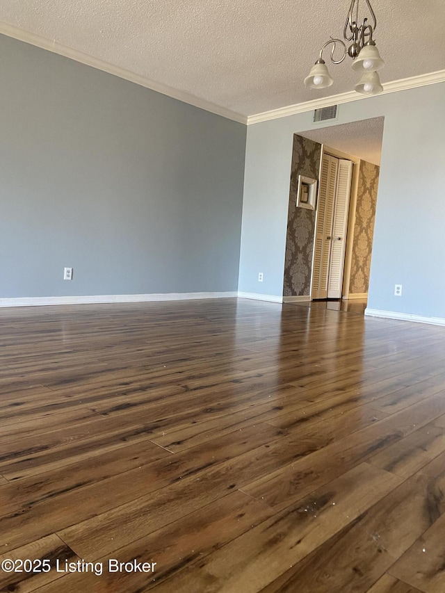 unfurnished room featuring ornamental molding, dark hardwood / wood-style floors, a chandelier, and a textured ceiling