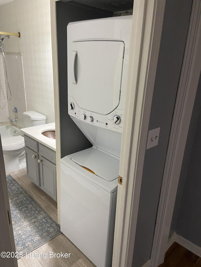 clothes washing area featuring stacked washer / dryer and wood-type flooring