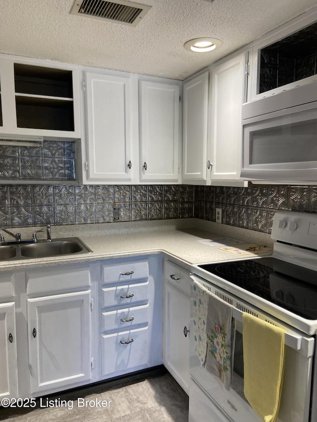 kitchen with tasteful backsplash, sink, white cabinets, and white appliances